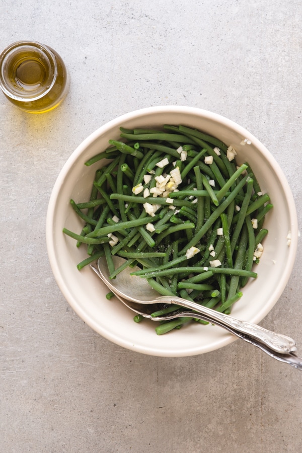 cooked green beans with chopped garlic in a white bowl