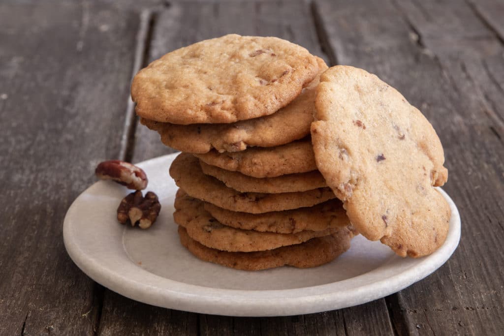 Pecan cookies stacked with one leaning on them.