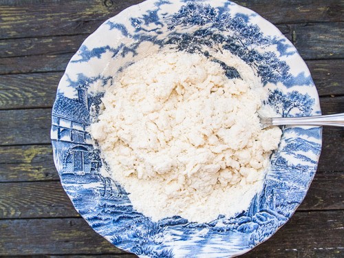 butter cut into flour in a blue bowl to make homemade pie dough