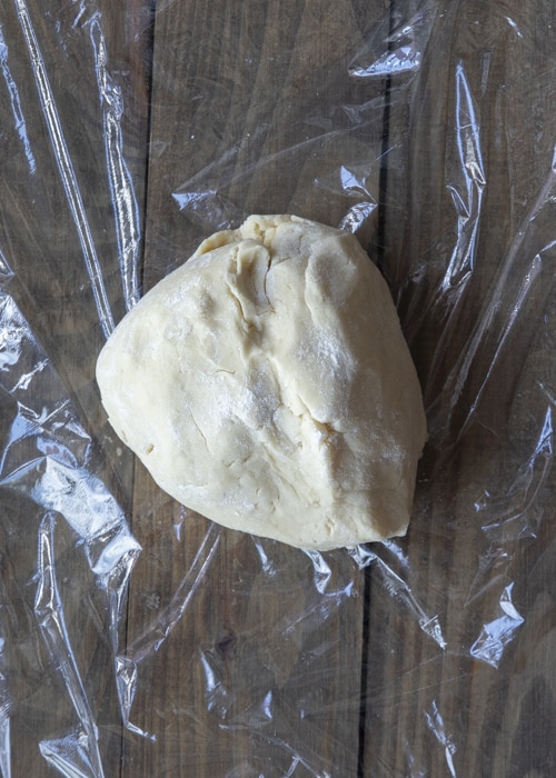 The dough shaped and on plastic wrap.