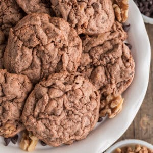 Chocolate chip walnut cookies on a white plate.