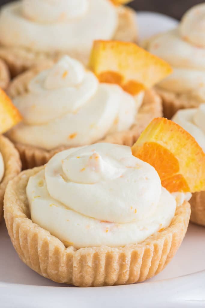 Orange cheesecake tarts on a white board.