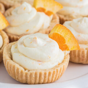 Orange cheesecake tarts on a white board.