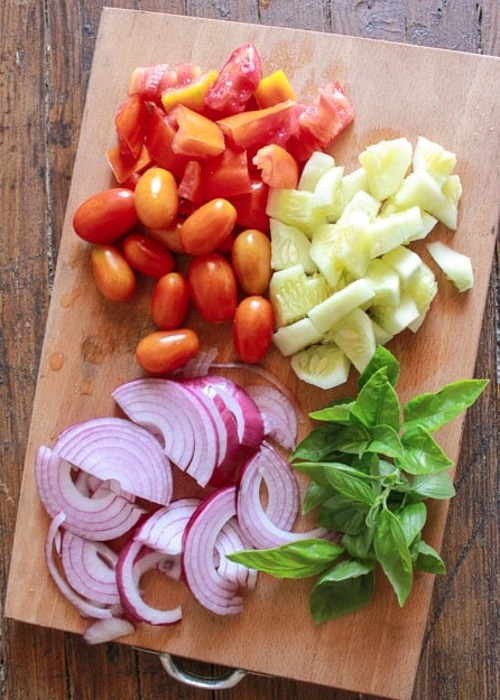 ingredients for panzanella sliced onion, tomatoes cucumber.