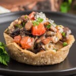 Parmesan potato basket on a black plate.