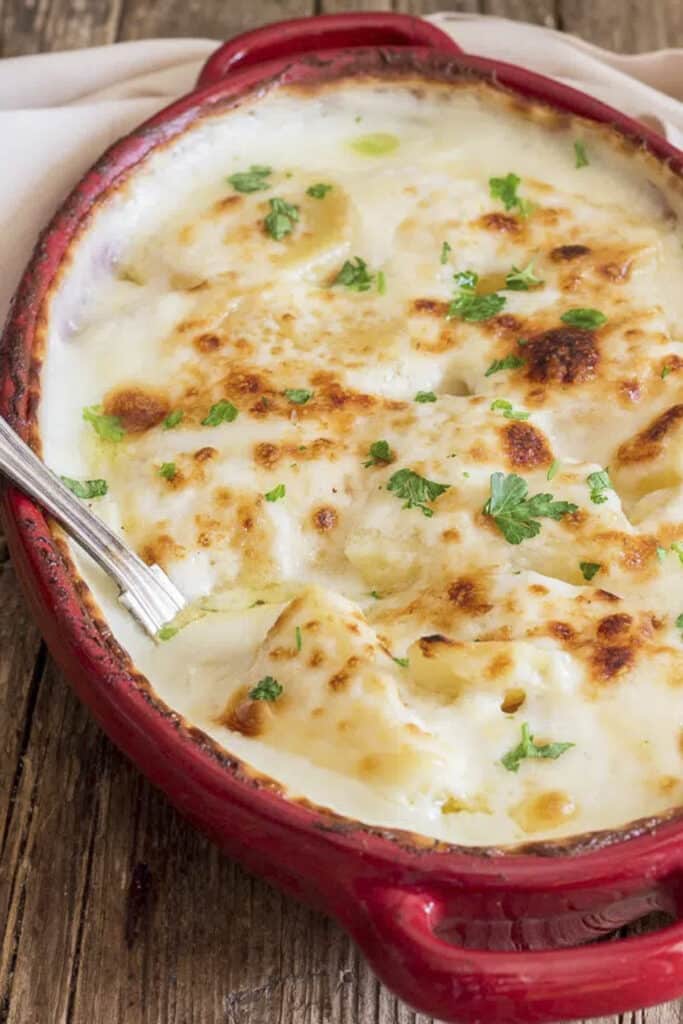 Scalloped potatoes in a red dish.