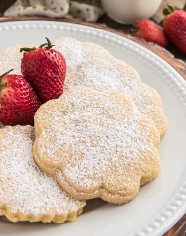 Strawberry cookies on a white plate with two strawberries.