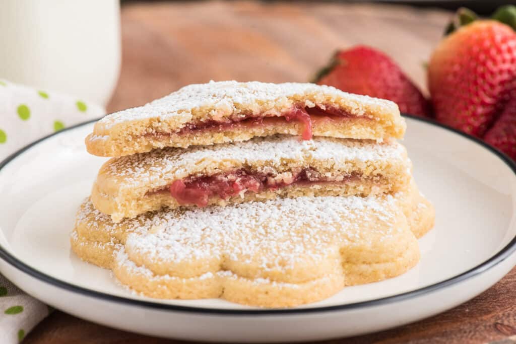 Two strawberry cookies stacked with one cut in half stacked.