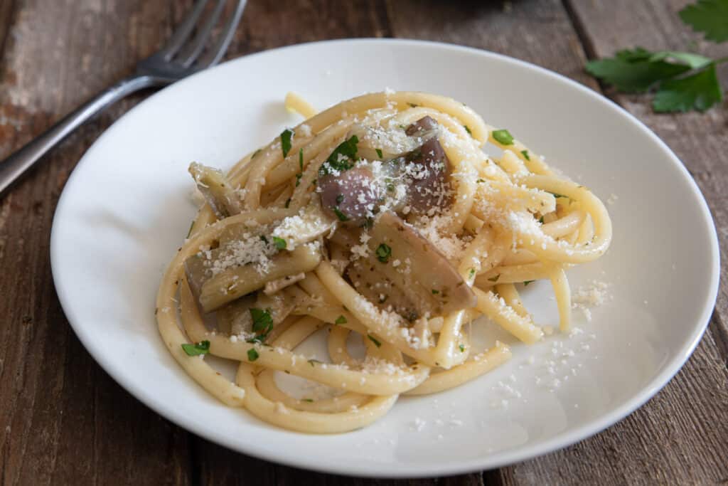 Pasta with eggplant and parmigiano on a white plate.