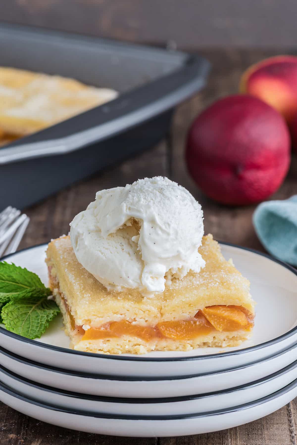 A slice of peach crostata with a scoop of ice cream.