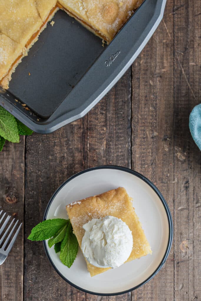 The crostata in a pan and a slice on a white plate.