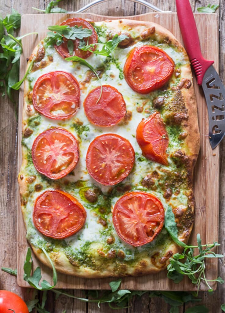 Pesto Pizza on a wooden board.