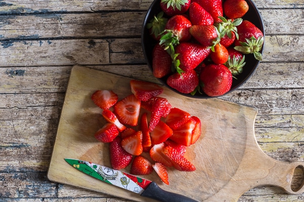  freezing strawberries slices on a board and whole in a bowl