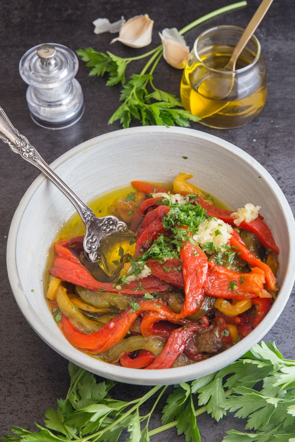 roasted peppers in a white bowl with the spices and garlic