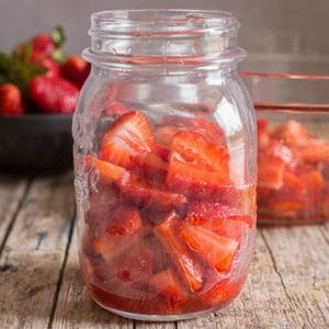 Sliced strawberries in a glass jar.