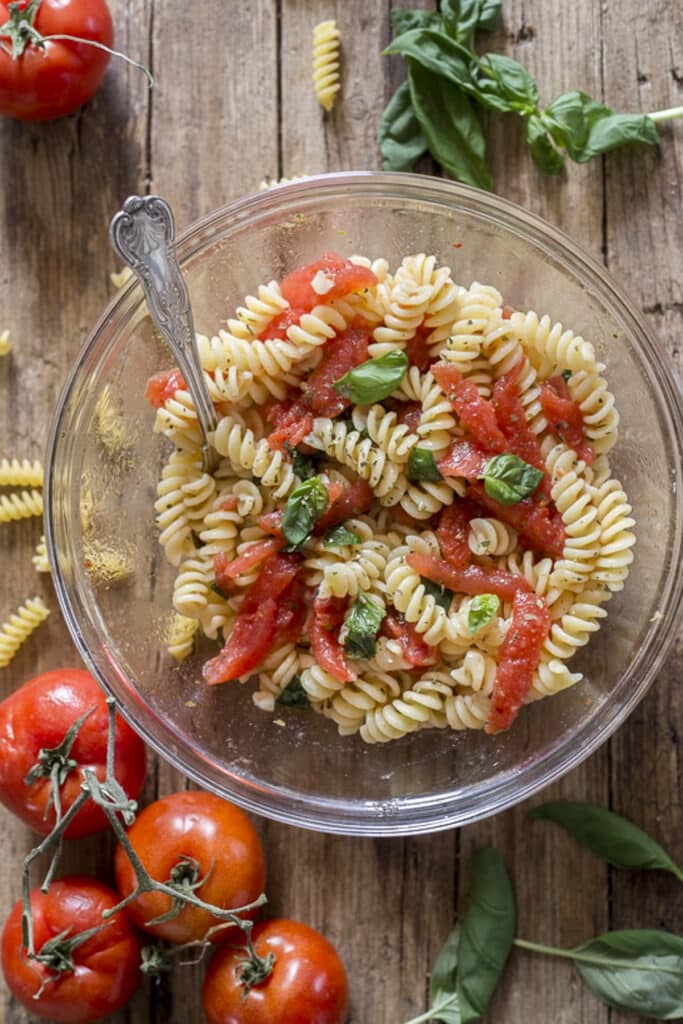 Tomato pasta salad in a glass bowl.