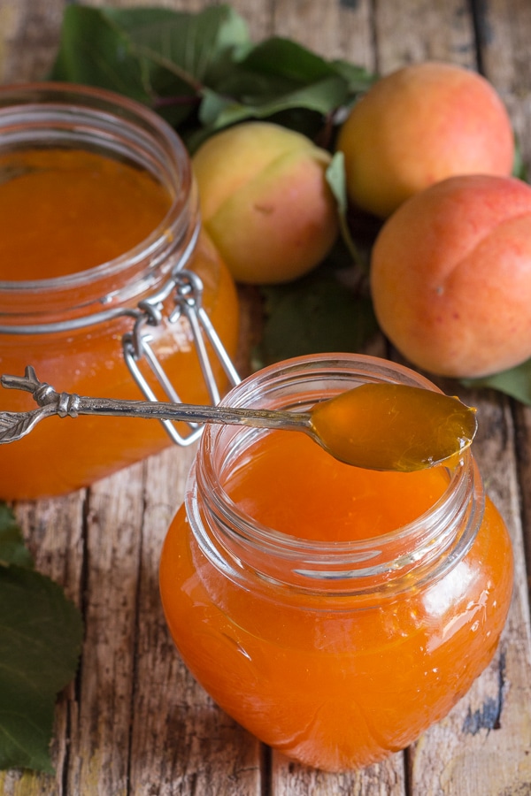 apricot jams in 2 jars with a spoonful of jam on the rim