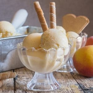 3 scoops of peach ice cream in a glass dish.