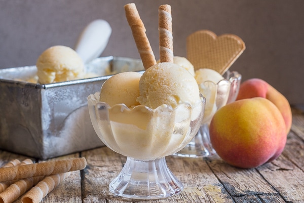 fresh peach ice cream in a bowl with fresh peaches