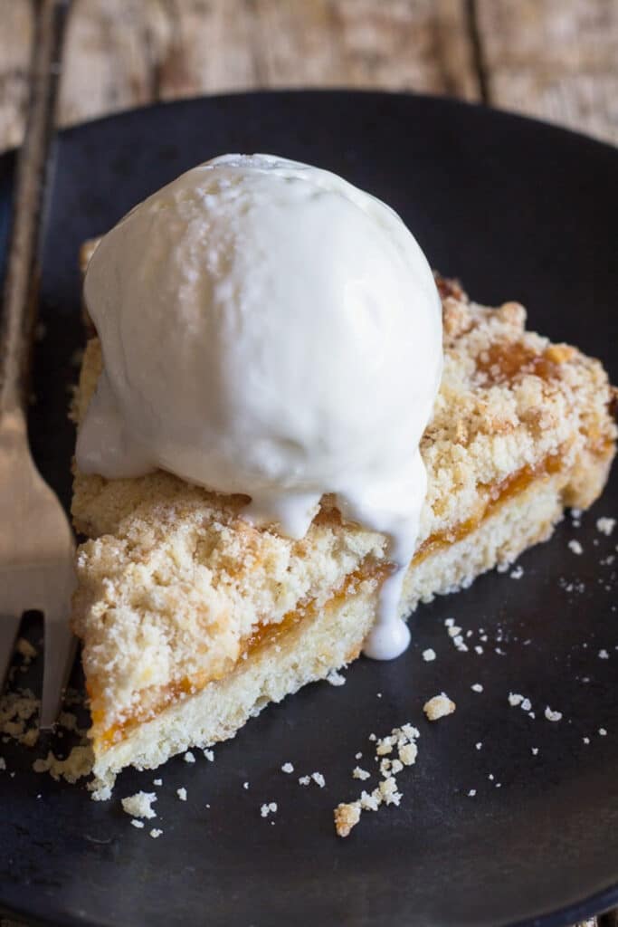 A slice of crumb pie with a scoop of vanilla ice cream.