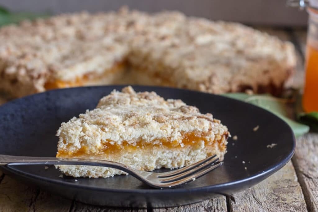 Crumb pie and a slice on a black plate.