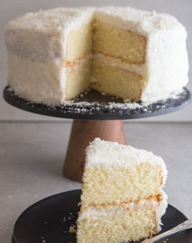 coconut cake with a slice on a black plate