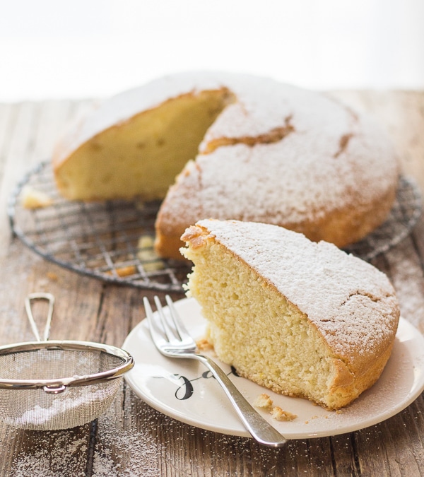 hot milk cake with a slice on a white plate