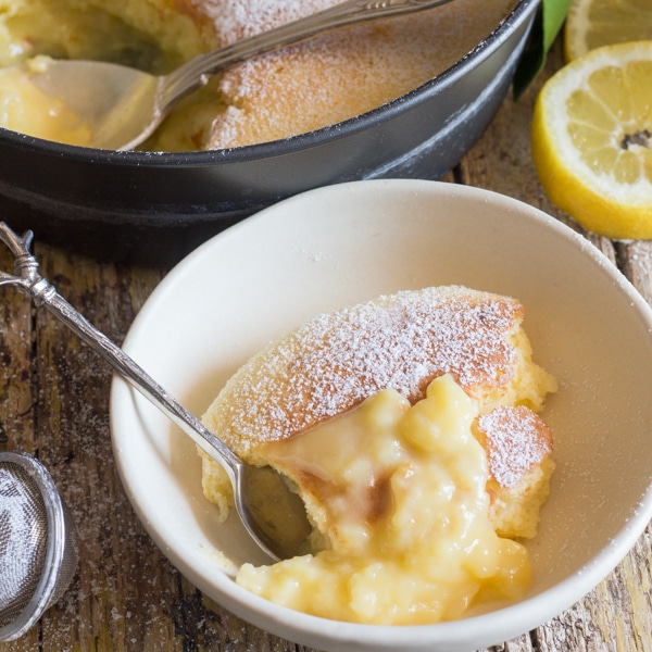 up close lemon pudding cake in a white bowl.