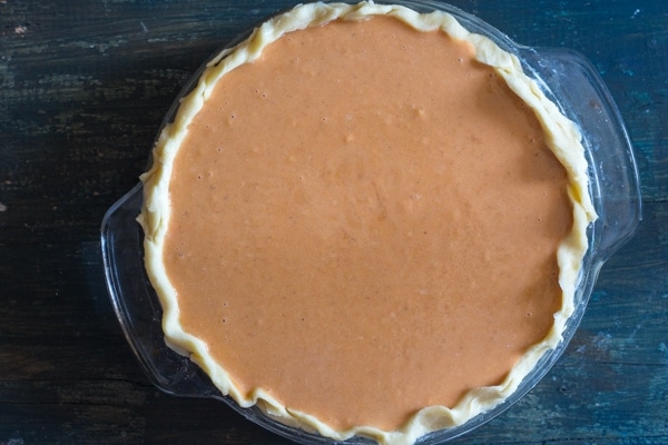 Pumpkin pie filling in crust ready for baking