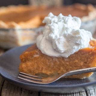 slice of pumpkin pie and maple whipped cream on a black plate