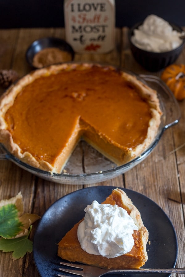 pumpkin pie in a glass dish and one slice on a black plate