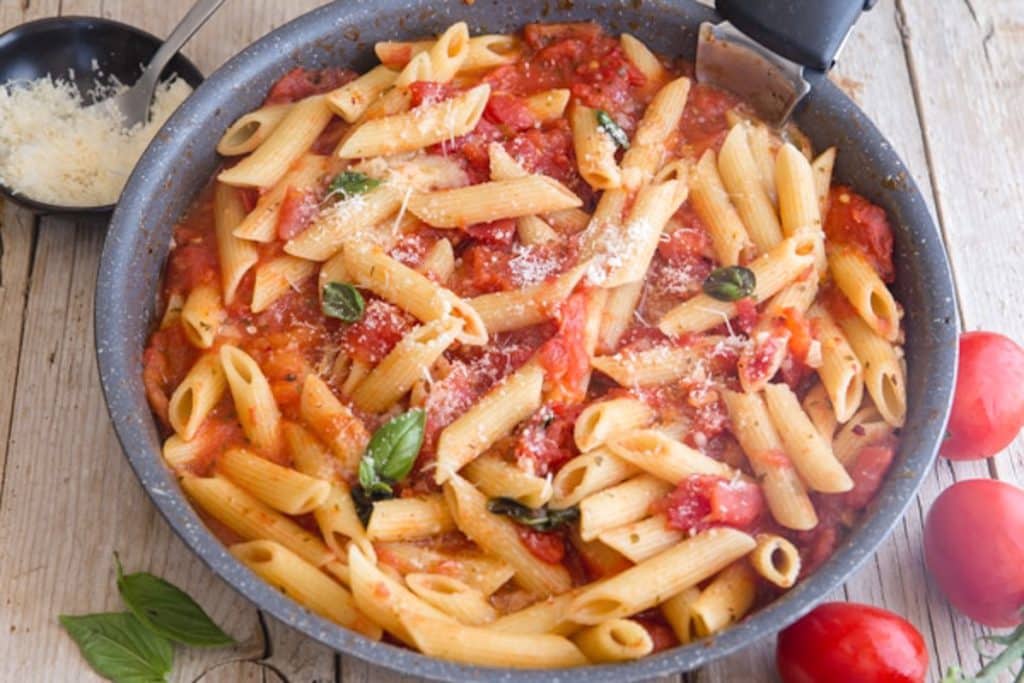 Tomato sauce and pasta in a black pan.