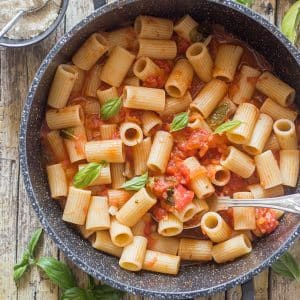 Fresh tomato sauce and pasta in a black pan.
