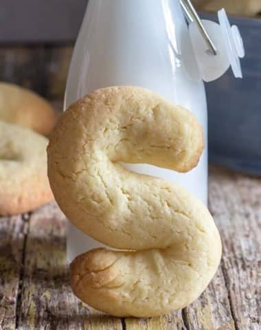 An s cookie leaning against a jar of milk.