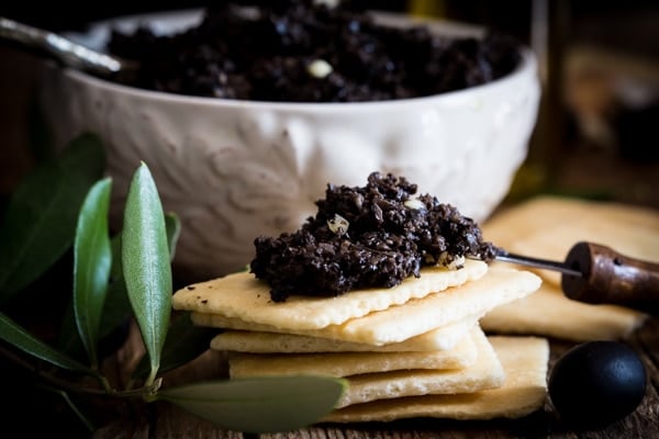 black olive tapenade in a bowl and on a cracker