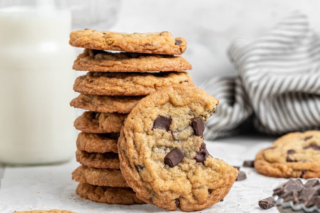 Chocolate chunk cookies stacked with one leaning with a bite out.