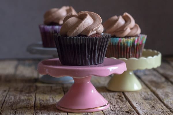 3 chocolate cupcakes on small cake stands