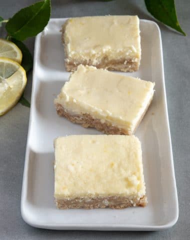 3 lemon cheesecake squares on a white dish.