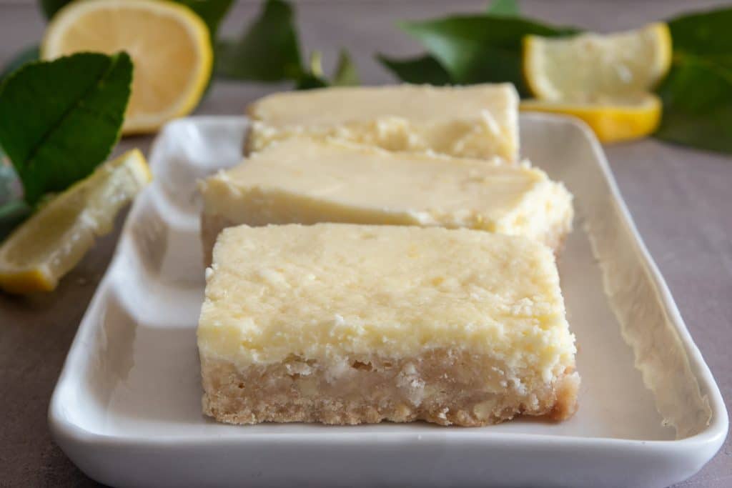 Lemon cheesecake squares on a white plate.