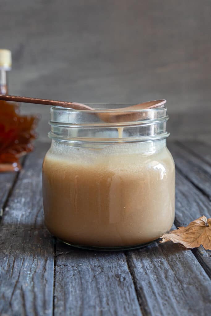 Maple caramel sauce on a spoon and in a jar.