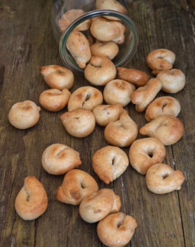 taralli falling out of a jar on a wooden board.