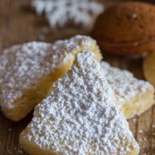 Italian almond cookies sprinkled with powdered sugar on a wooden board