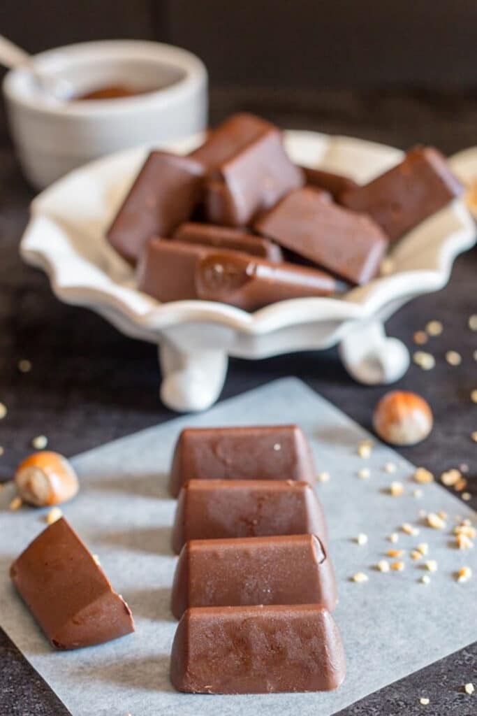 Chocolates in a white dish and some on parchment paper.