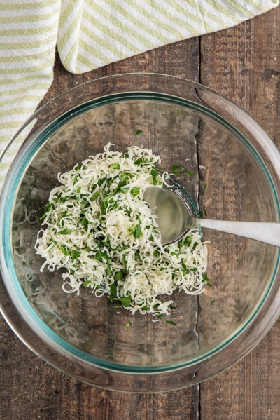 Parmesan cheese and parsley mixed in a small glass bowl.