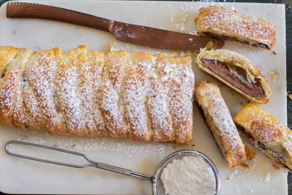 Chocolate pastry braid with three slices cut.