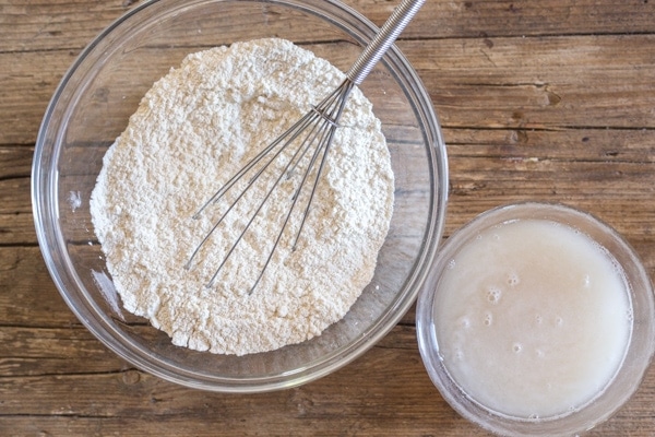 flour in a glass bowl, and yeast mixture in a small bowl to make focaccia pugliese