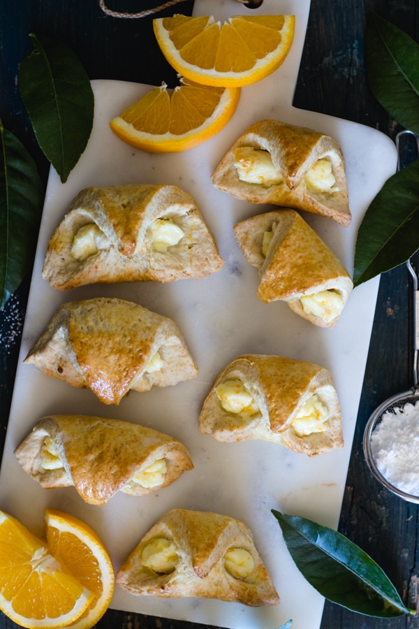 orange cream cheese filled baked croissant on a white board