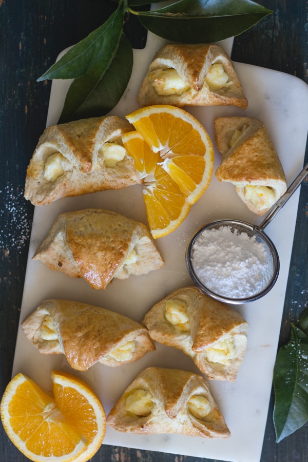 orange cream cheese filled baked croissant on a white board
