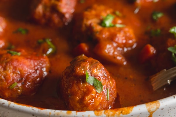 up close Italian meatballs with a pepper sauce in a white pan