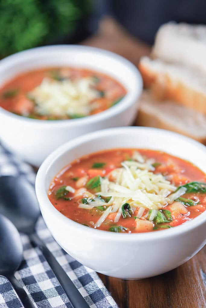 Soup in two bowls with cheese on top.